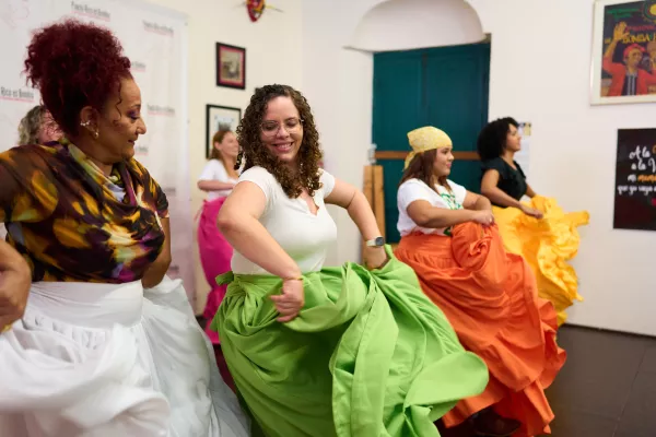 Women dancing traditional Puerto Rican bomba in a studio, wearing colorful skirts and moving in rhythm together.
