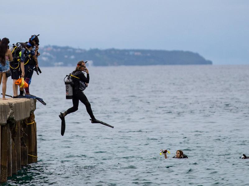 Dive instructor jumps into ocean at Crash Boat Beach.
