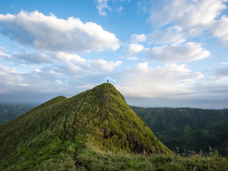 A person stands at the peak of mountain in the central region of puerto rico.