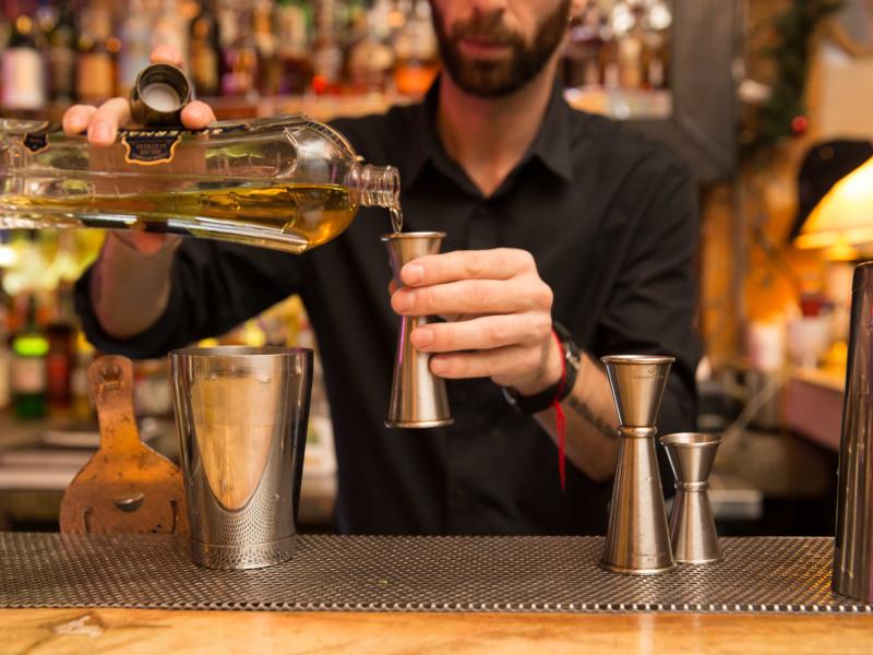 A bartender measures a pour of liqueur for a cocktail