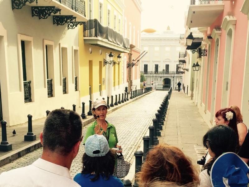 A female tour guide leads a group on a walking tour of Old San Juan.