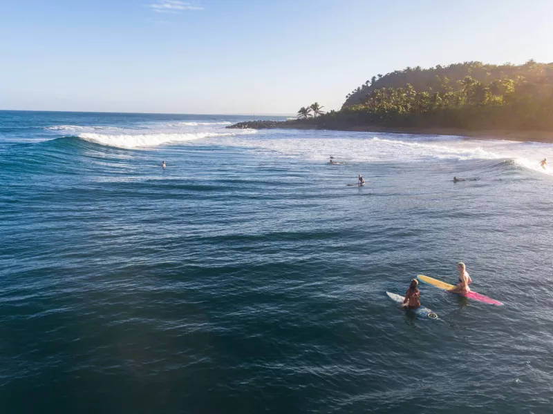 Anticipation builds as two surfers await the next set at Domes Beach in Rincón, a renowned Puerto Rican surf spot.