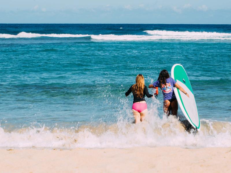 Two women run through the waves at Jobos Beach in Isabela. 