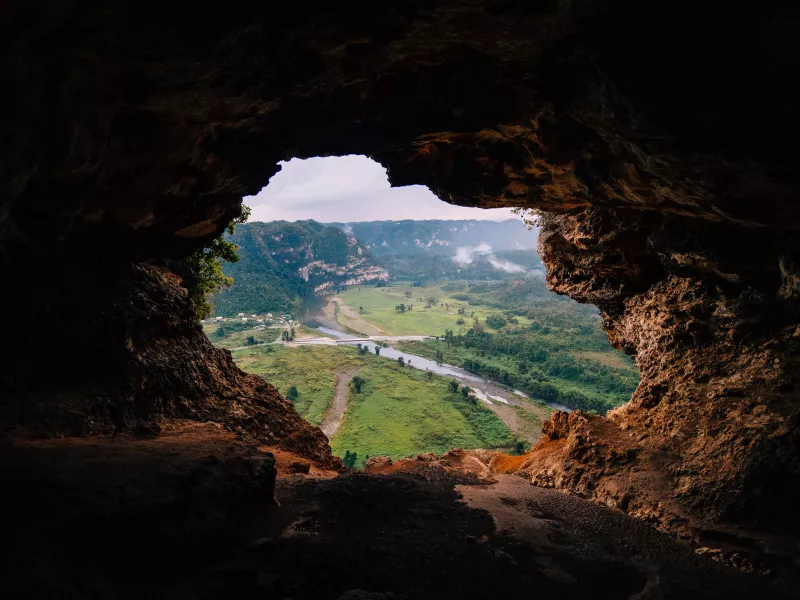 A cave opening reveals a green valley at Cueva Ventana.