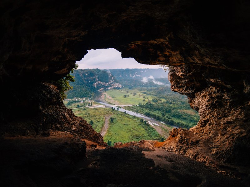 A cave opening reveals a green valley at Cueva Ventana.