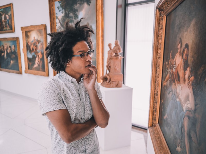 A man admires a historic painting hanging in a museum