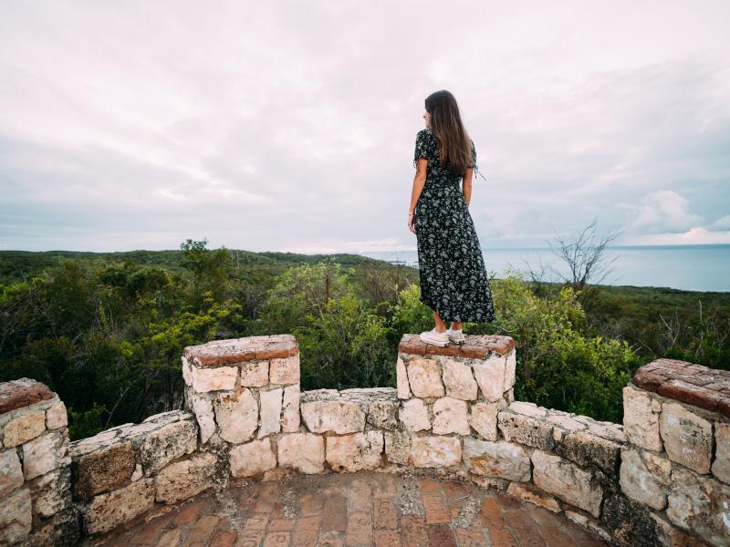 A woman peers over Guánica Dry Forest from the top of Fuerte Capron.