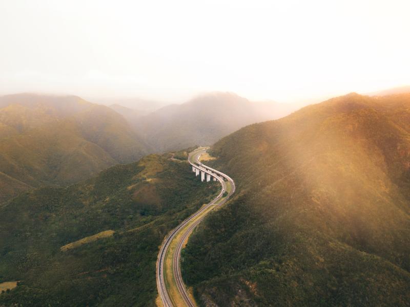 Aerial shot showing a curving stretch of highway winding through a mountain pass
