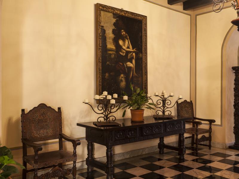 A historic painting hangs on a wall inside el convento hotel