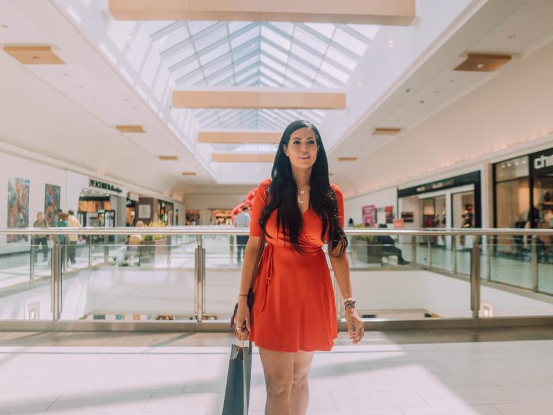 A woman walks through the mall with a bag in her hand