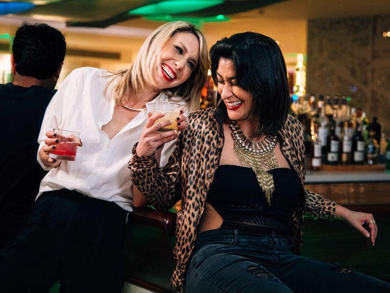 A couple of lesbians enjoying their cocktails at a bar.