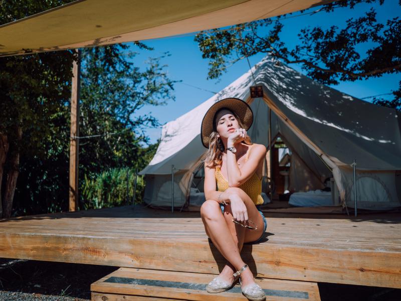 A girl sits in front of a camping tent at Pitahaya Glamping.