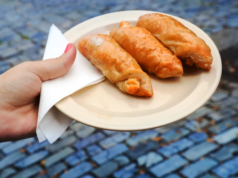 A woman's hand holding a plate with quesitos, traditional Puerto Rican pastries.