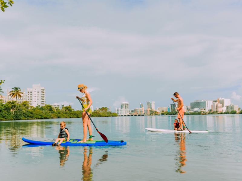 A family paddle boards at the Condado lagoon.