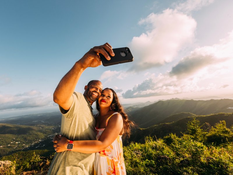 A couple takes a selfie with a backdrop of lush mountains in Puerto Rico's central region.