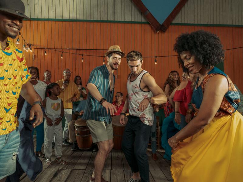 Two men dance with local dancers in Pinones, Puerto Rico