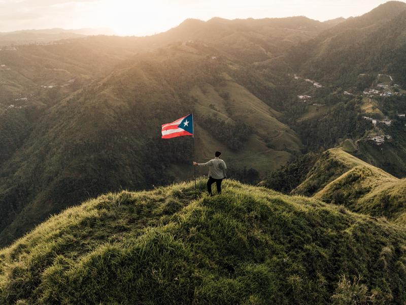 man in the mountains with Puerto Rico flag