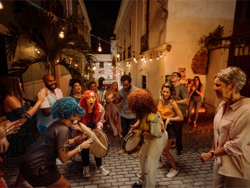 A group of people play instruments and dance in the street in Old San Juan