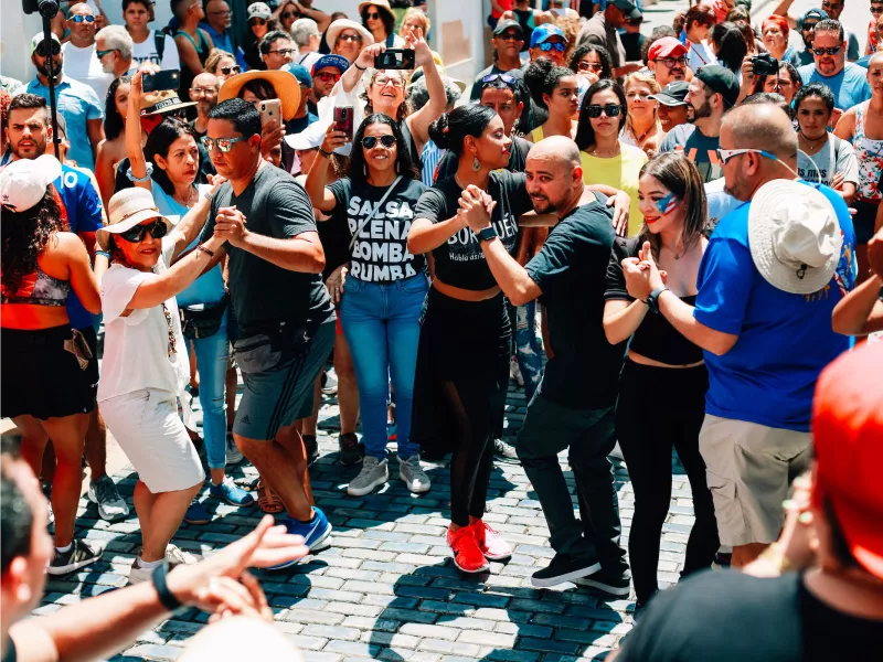 A joyful crowd participates in salsa dancing in the streets of historic Old San Juan, a lively display of Puerto Rican culture and community spirit.