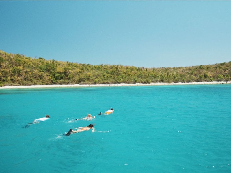 A group of people snorkel on clear turquoise water at Flamenco Beach in Culebra.