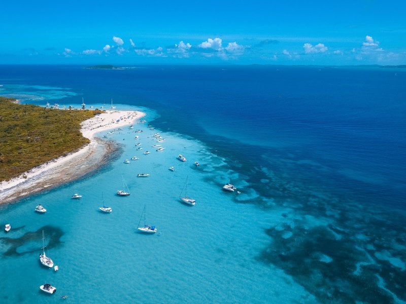 Vista aérea de la costa de Cayo Icacos en la costa este de Puerto Rico, con agua azul clara y varios barcos anclados cerca de la orilla.