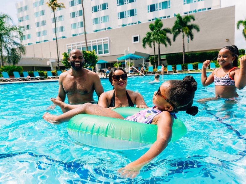 A family with two parents and two kids plays in a resort pool in Puerto Rico.