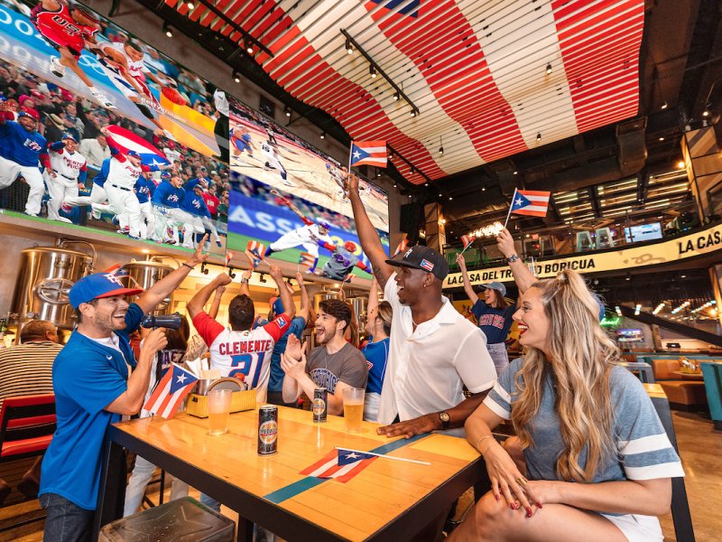 A group celebrates Puerto Rico's baseball team at the Arena Medalla lounge in Distrito T-Mobile