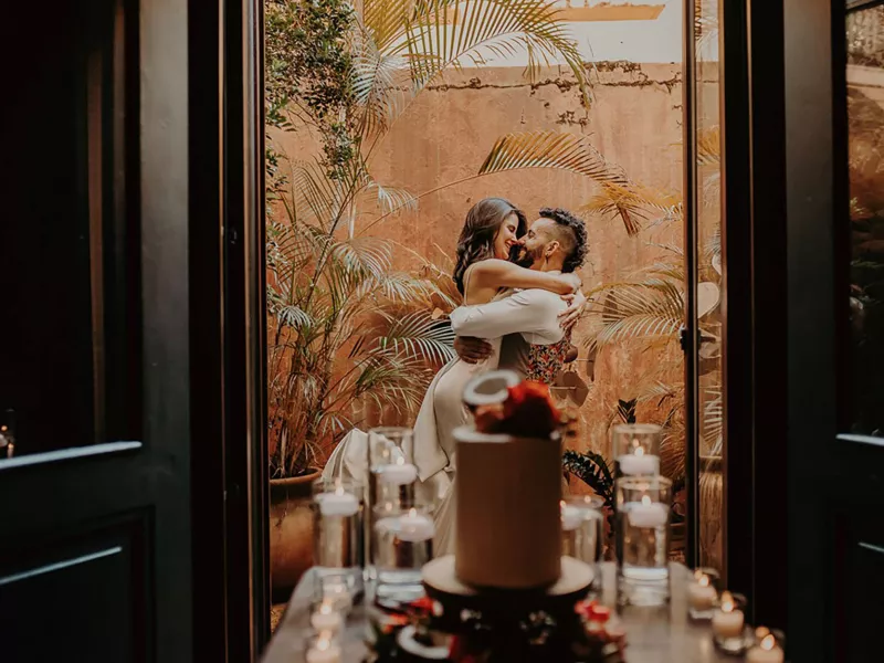 A couple embraces on a balcony at Hotel El Convento with a wedding cake in the foreground — a romantic venue for Puerto Rico wedding packages.
