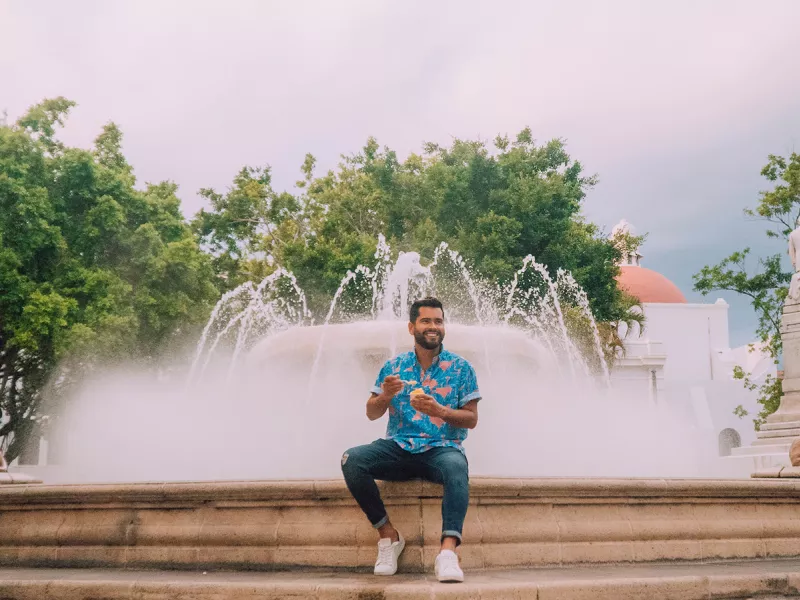 Man enjoying his ice cream while sitting on the ledge of a large fountain in downtown Ponce.
