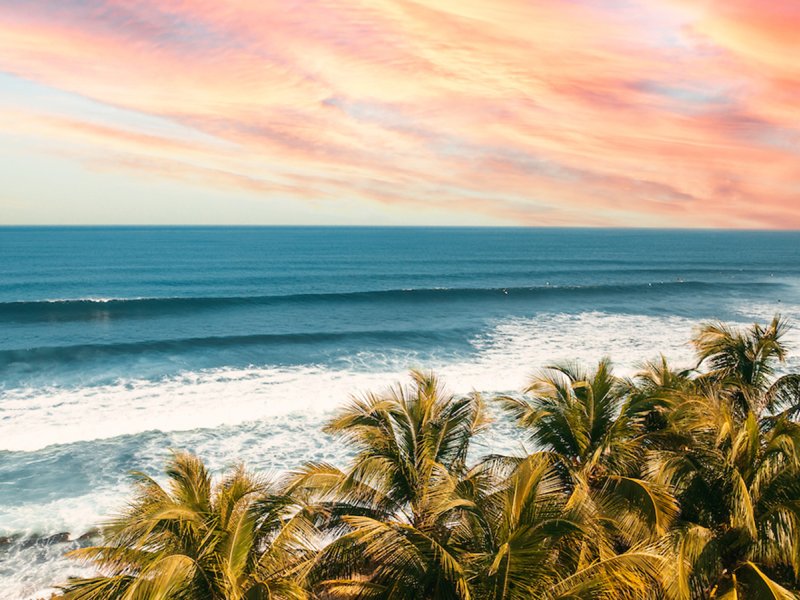 The sun setting, painting the sky a color of orange and pink, over the pristine waters of the beaches in Aguadilla, Puerto Rico.