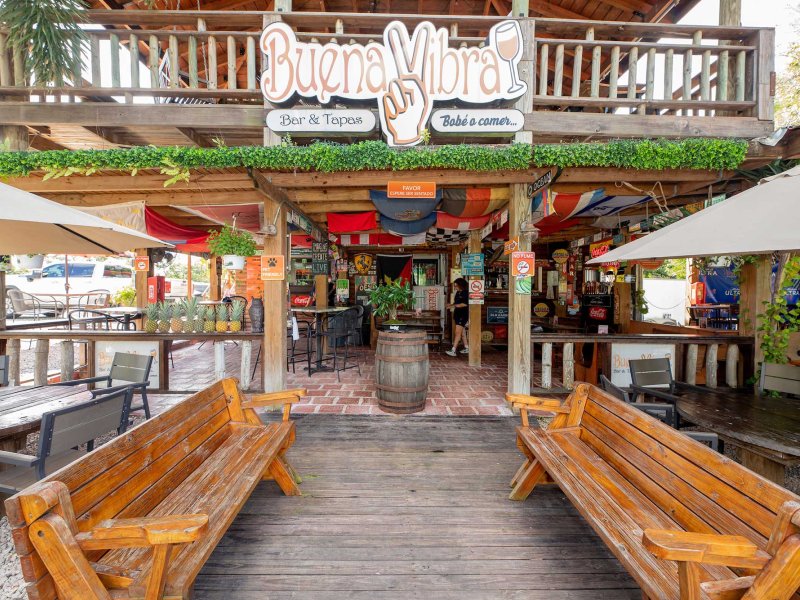 Exterior of a two-story beach bar and restaurant in Cabo Rojo, Puerto Rico, with two wooden benches sitting in the front.