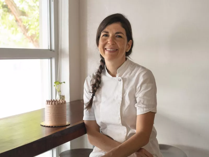 Chef Lucía at her patiserrie posing next to a cake.