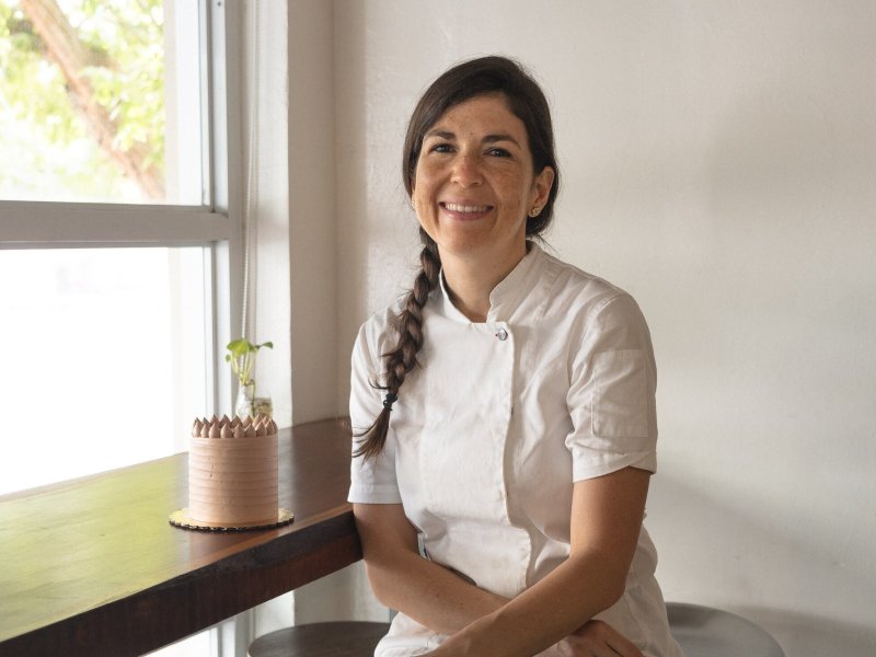 Chef Lucía at her patiserrie posing next to a cake.