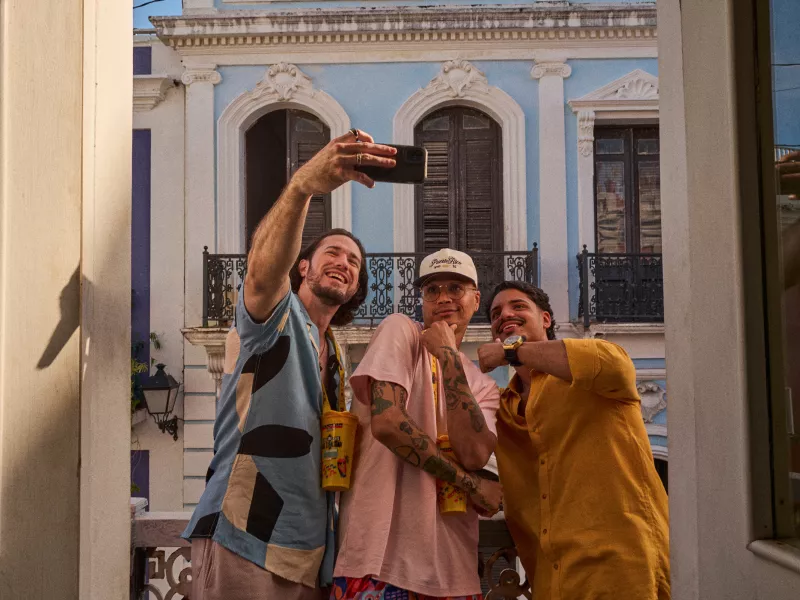 Three friends taking a selfie in front of a colorful historic building in Old San Juan during golden hour.
