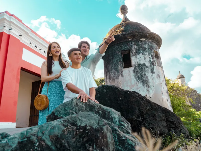 A family of three people standing at the front of a Garita while the dad is pointing at the horizon.