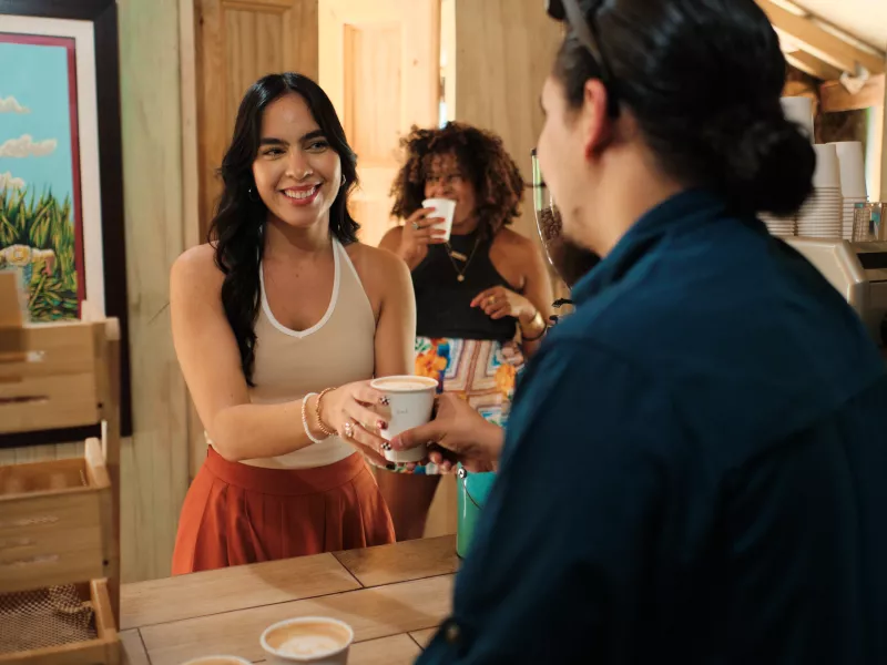 A woman receiving her cup of coffee at a rustic alike coffee shop.