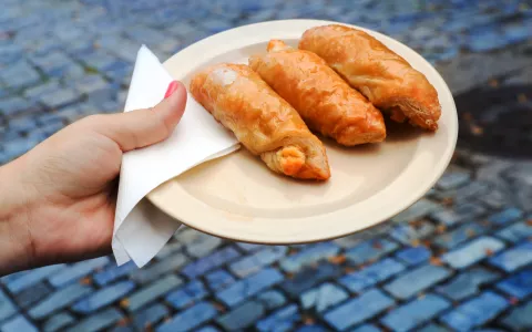 A woman's hand holding a plate with quesitos, traditional Puerto Rican pastries.