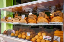 Display case filled with traditional Puerto Rican fritters and empanadas at the Kioskos de Luquillo, labeled with fillings like shrimp, lobster, crab, and beef.
