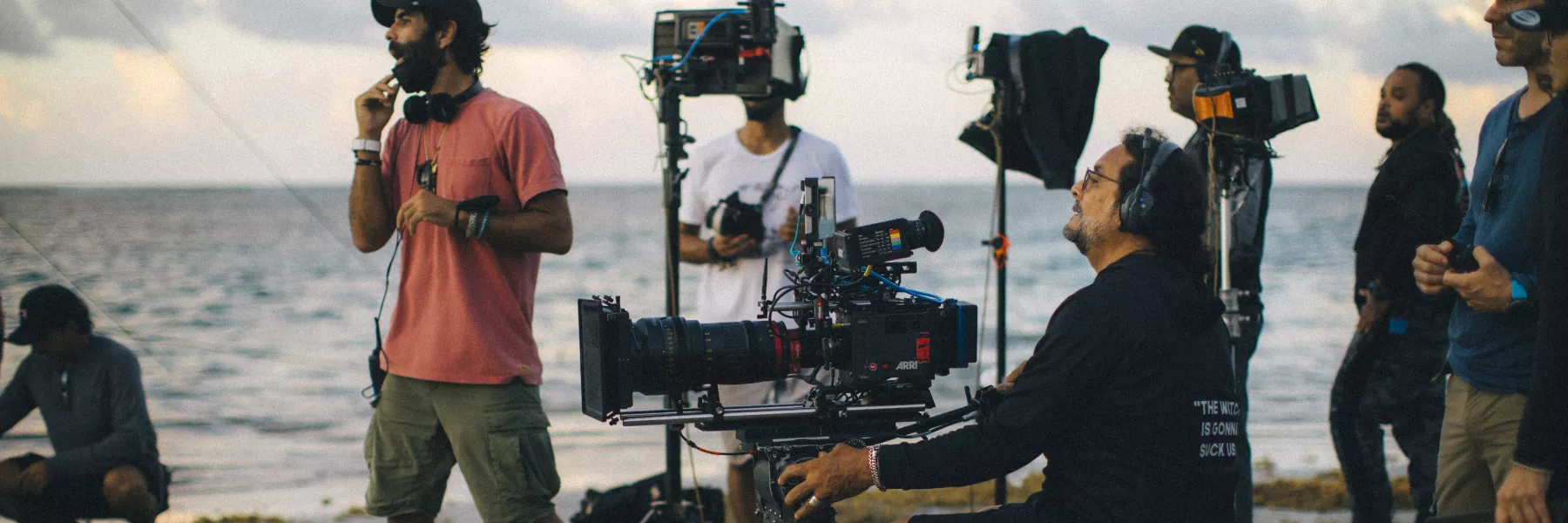 Group of people filming with cameras at the beach.