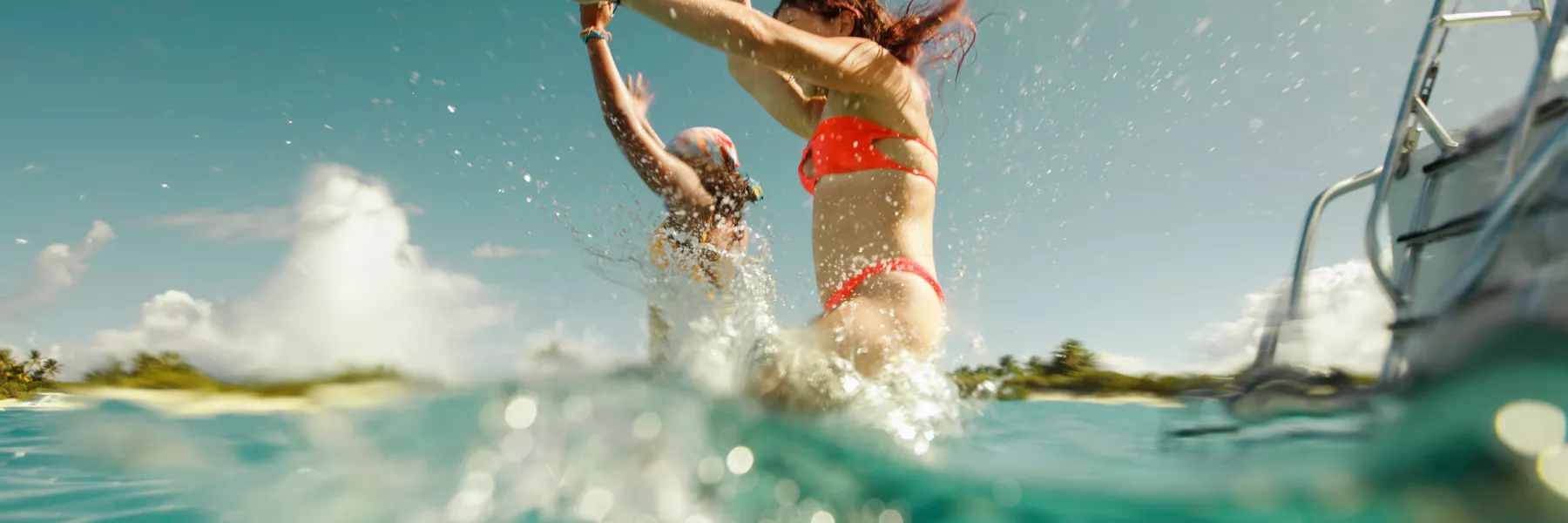 Two travelers leap from a boat into the crystal-clear waters of Icacos Island in Fajardo, Puerto Rico, splashing into the turquoise sea on a sunny day.