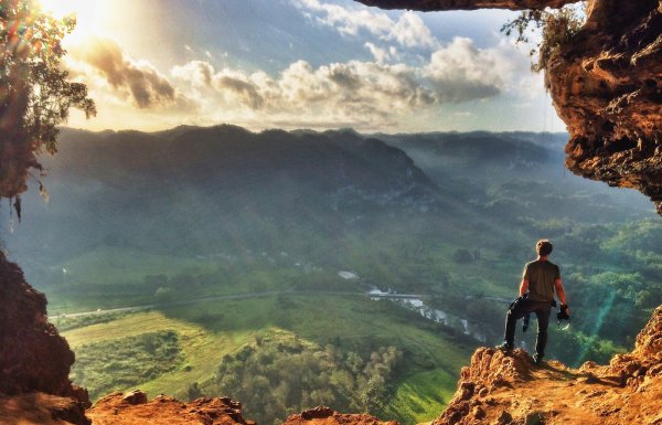 A hiker stands at the mouth of Cueva Ventana.