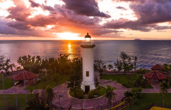 The sun sets behind a lighthouse in Rincón.