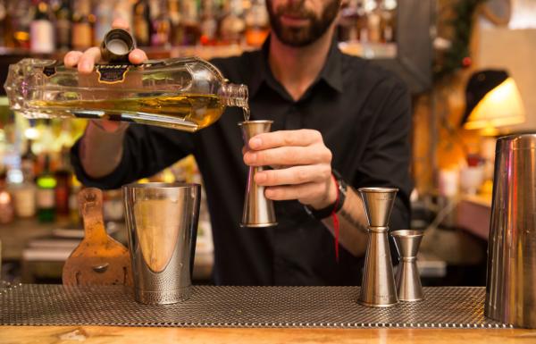 A bartender measures a pour of liqueur for a cocktail