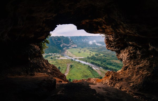 A cave opening reveals a green valley at Cueva Ventana.