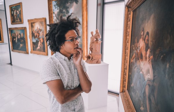 A man admires a historic painting hanging in a museum