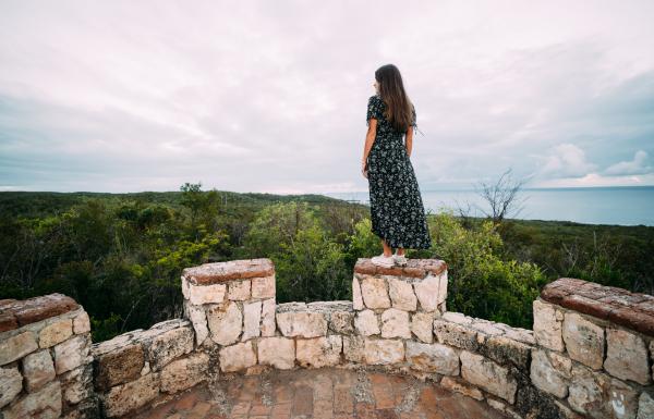 A woman peers over Guánica Dry Forest from the top of Fuerte Capron.