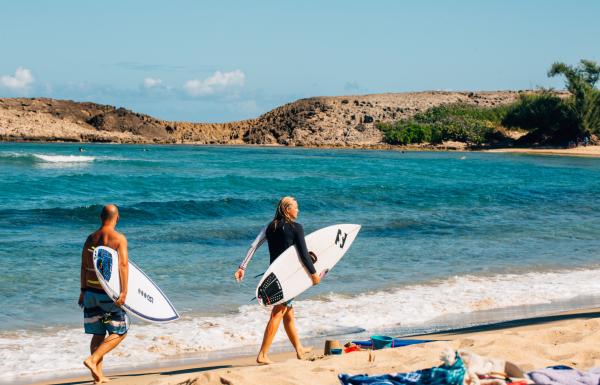 Two surfers stroll along Jobos Beach in Isabela, Puerto Rico.