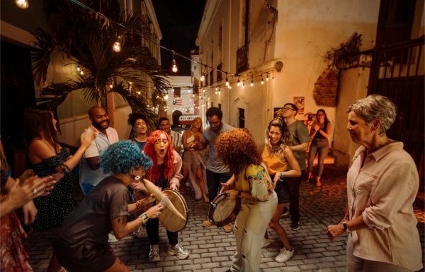 A group of people play instruments and dance in the street in Old San Juan