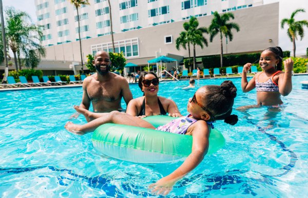 A family with two parents and two kids plays in a resort pool in Puerto Rico.