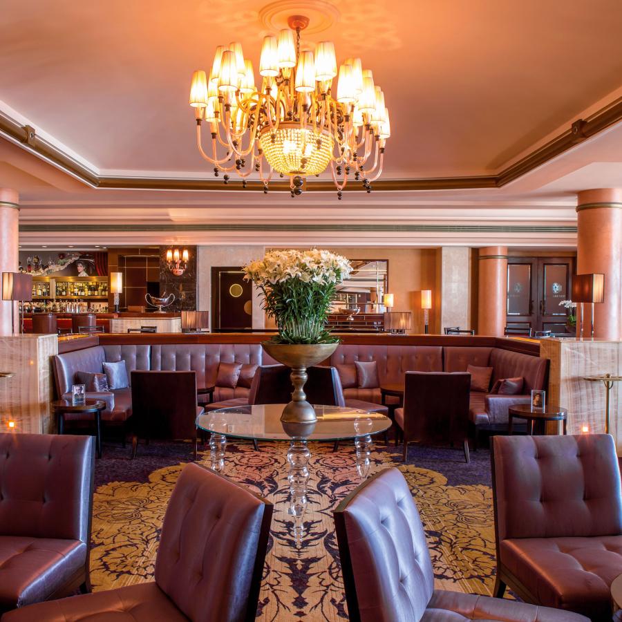 El elegante salón del hotel Condado Vanderbilt incluye tapicería de cuero, columnas de mármol y un candelabro adornado.